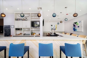 A modern kitchen with a central island, bar seating, and hanging pendant lights.