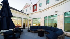 A patio area with outdoor seating, a wicker sofa, and a table. - Hilton Garden Inn Houston/Clear Lake NASA (Webster)
