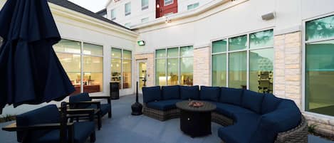 Un'area patio con posti a sedere all'aperto, un divano in vimini e un tavolo.