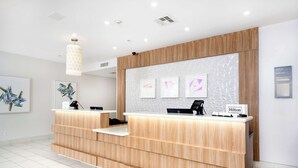 A modern reception desk with a wooden finish, a digital screen, and a sign indicating 'Hilton Honors'. - Hilton Garden Inn Houston/Clear Lake NASA (Webster)
