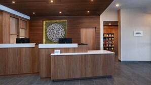 Ein Hotel-Empfangsbereich mit Holztresen, einem dekorativen Wandbild und einem Schild mit dem Hotelnamen.