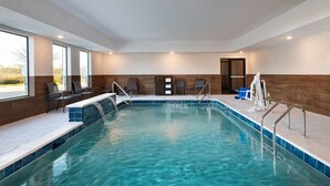 Ein überdachter Pool mit klarem, blauem Wasser, umgeben von einer gefliesten Terrasse und Metallgeländern.