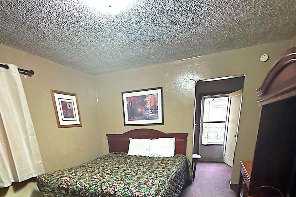 A bedroom with a bed, a dresser, a door, and two framed pictures on the wall.