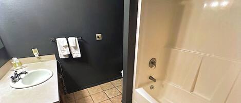 Ein Badezimmer mit Waschbecken, Spiegel, Handtuchhalter und Badewanne.