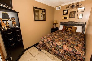 A bedroom with a large bed, a dresser, a mirror, and framed pictures on the wall. - Sandpiper Cove Studios By Holiday Isle (Destin)