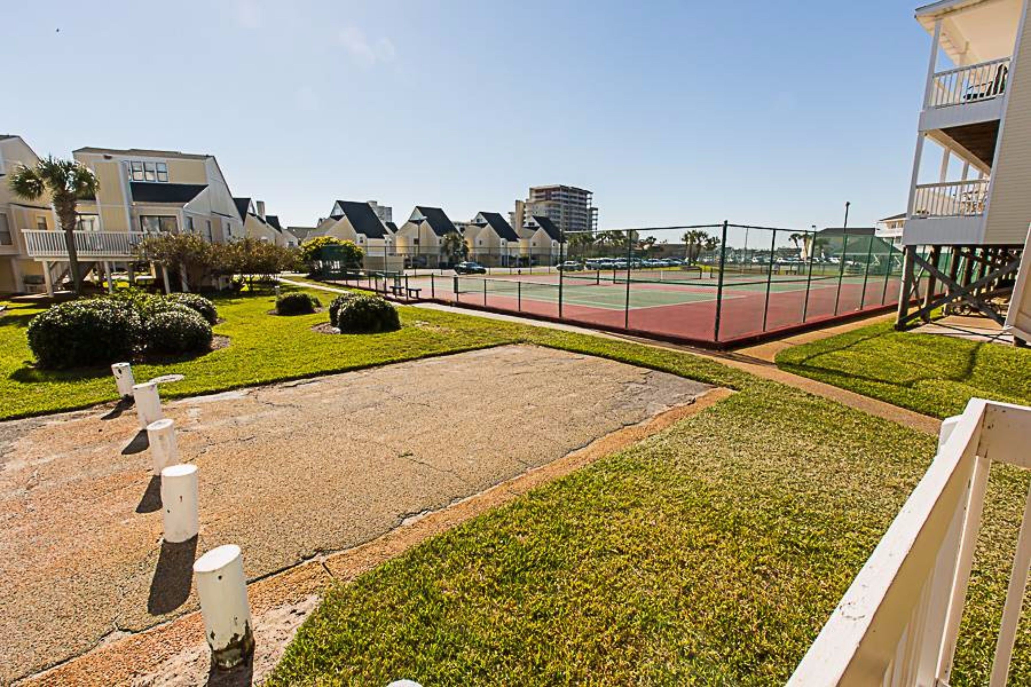 Un quartier résidentiel avec des maisons, un court de tennis et une pelouse.