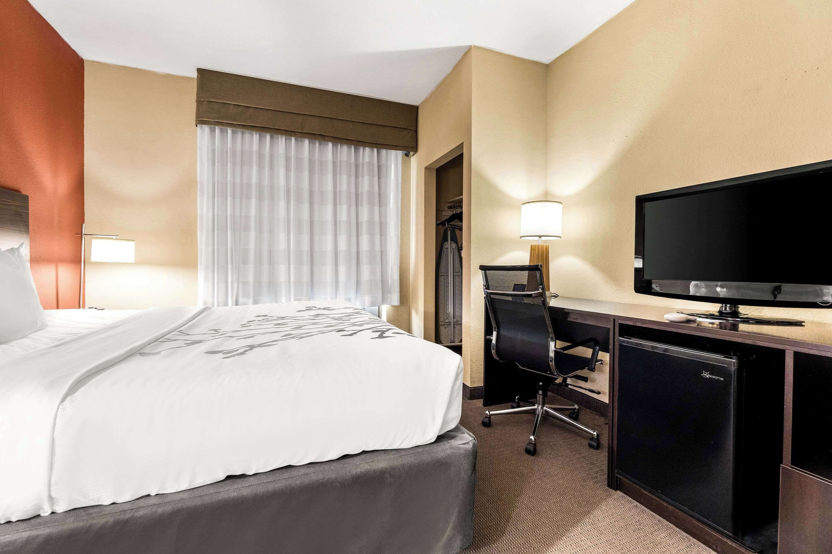 Une chambre d’hôtel comprenant un lit, un bureau avec une télévision, une chaise et une armoire.