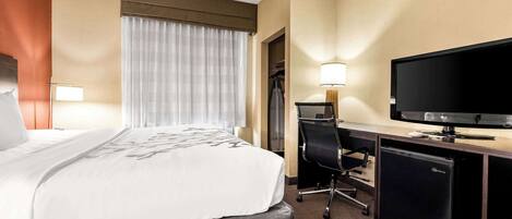Une chambre d’hôtel comprenant un lit, un bureau avec une télévision, une chaise et une armoire.