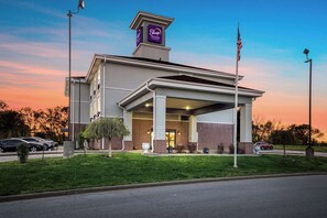 Un bâtiment de la chaîne Sleep Inn & Suites, avec une façade en briques, une entrée couverte et un drapeau américain.