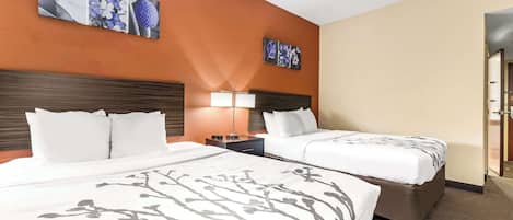 Una habitación de hotel con dos camas, una mesita de noche, una lámpara y decoración en la pared.
