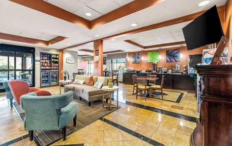 A hotel lobby with a seating area, a refreshment bar, and a large screen.