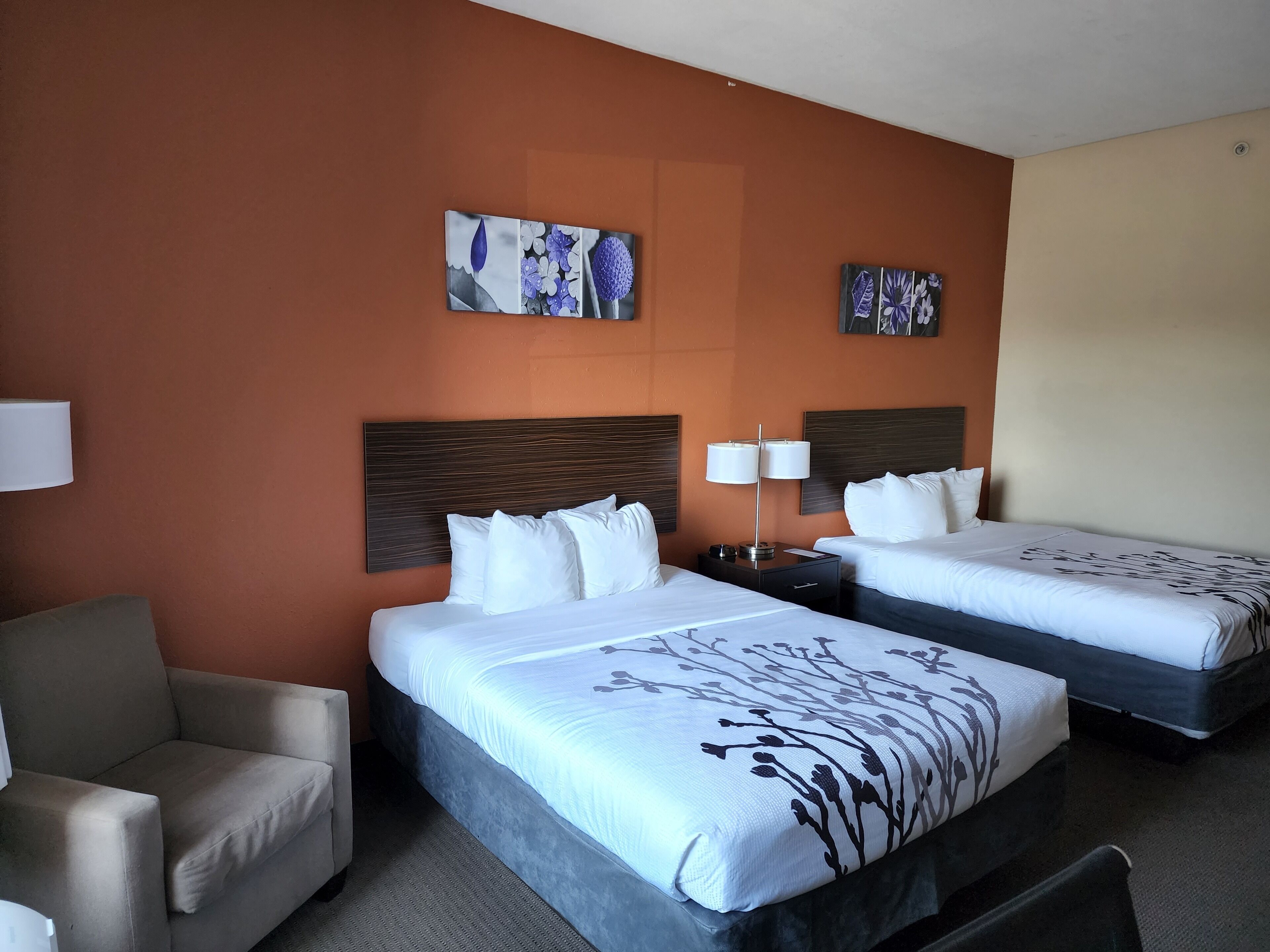 Una habitación de hotel con dos camas, un sofá y obras de arte en las paredes.