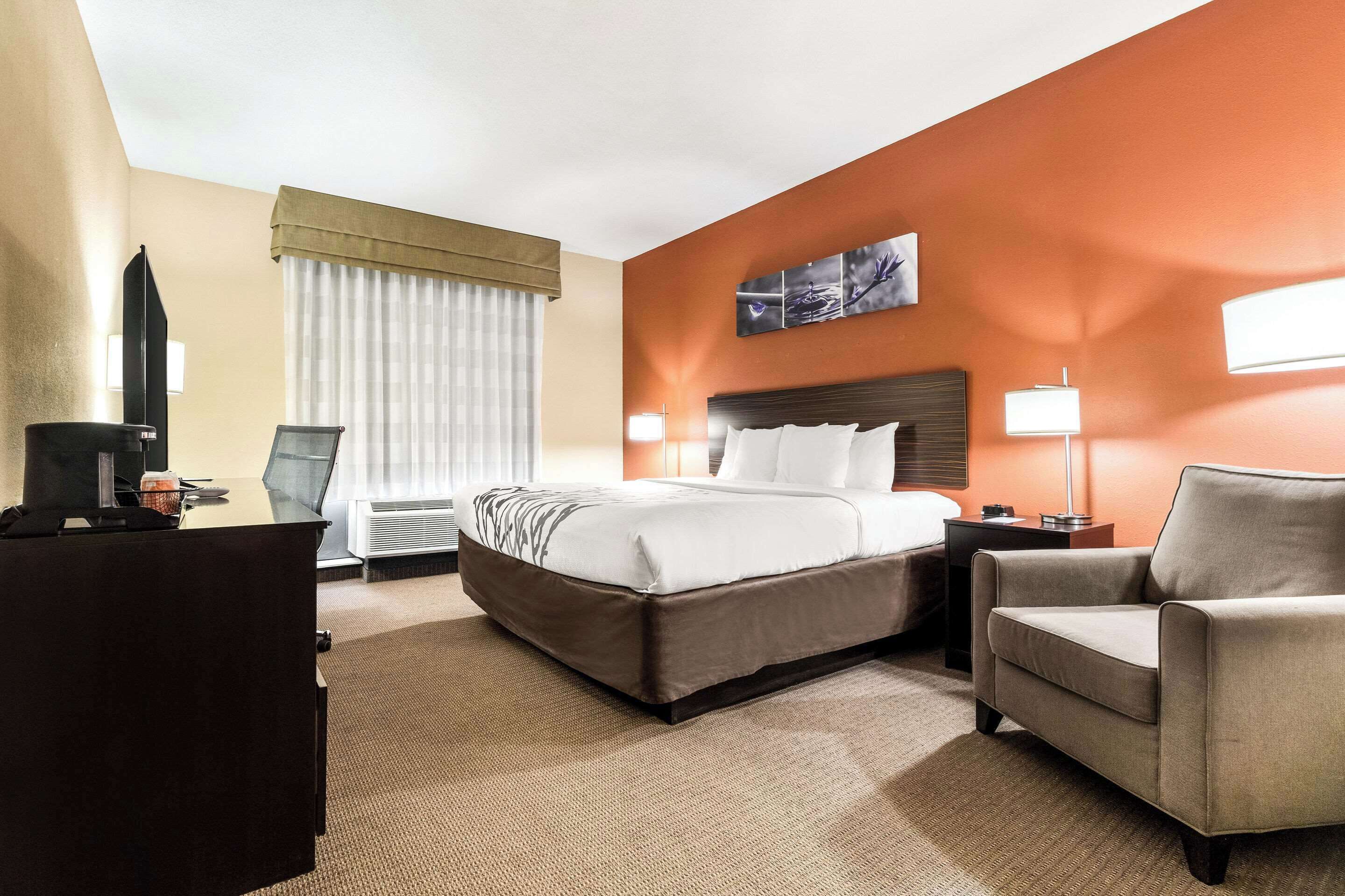 A hotel room with a large bed, a desk with a computer, a chair, and a TV.