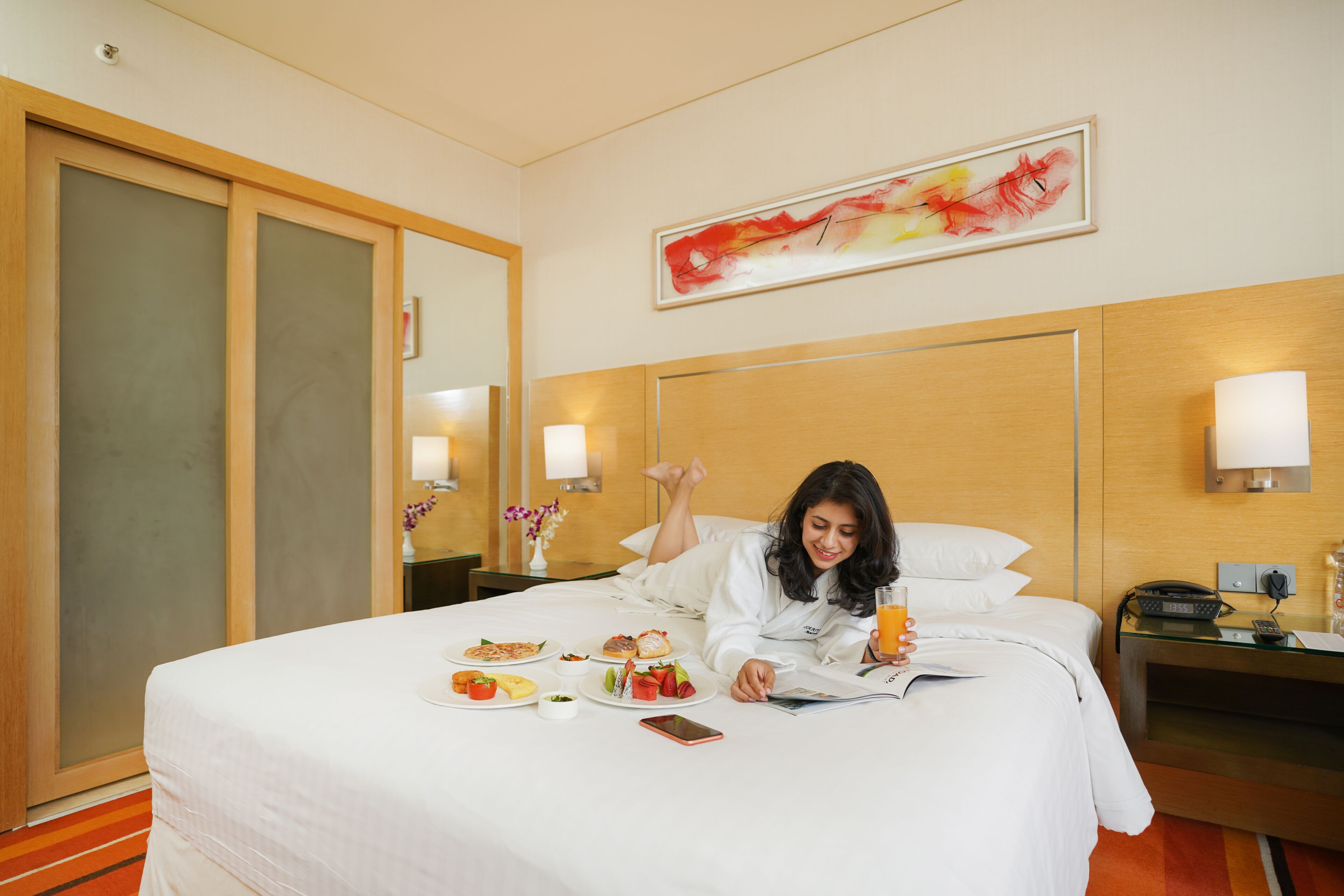 Ein Hotelzimmer mit Bett, Frühstückswagen und einem Bild an der Wand.