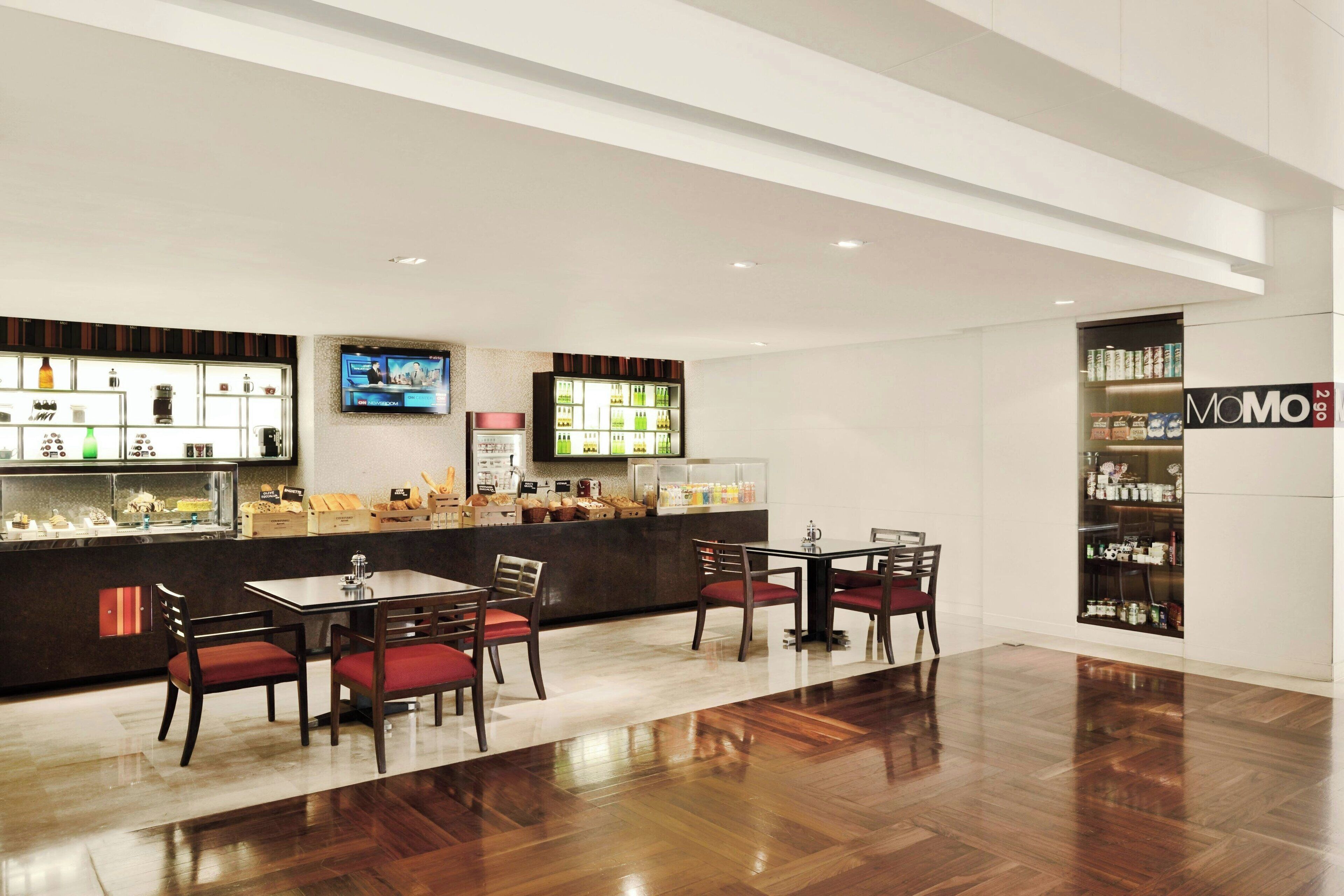 A modern hotel lobby with a bar area, seating, and a display of products.