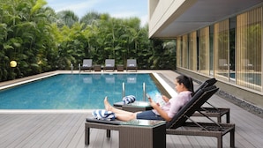 Zona de piscina con sillones de descanso, una piscina y vistas a vegetación exuberante.