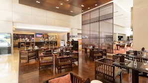 Un espacioso vestíbulo de hotel con mobiliario de madera, un amplio biombo decorativo y una zona de estar.