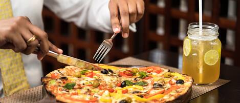 A pizza with various toppings and a drink with a straw.