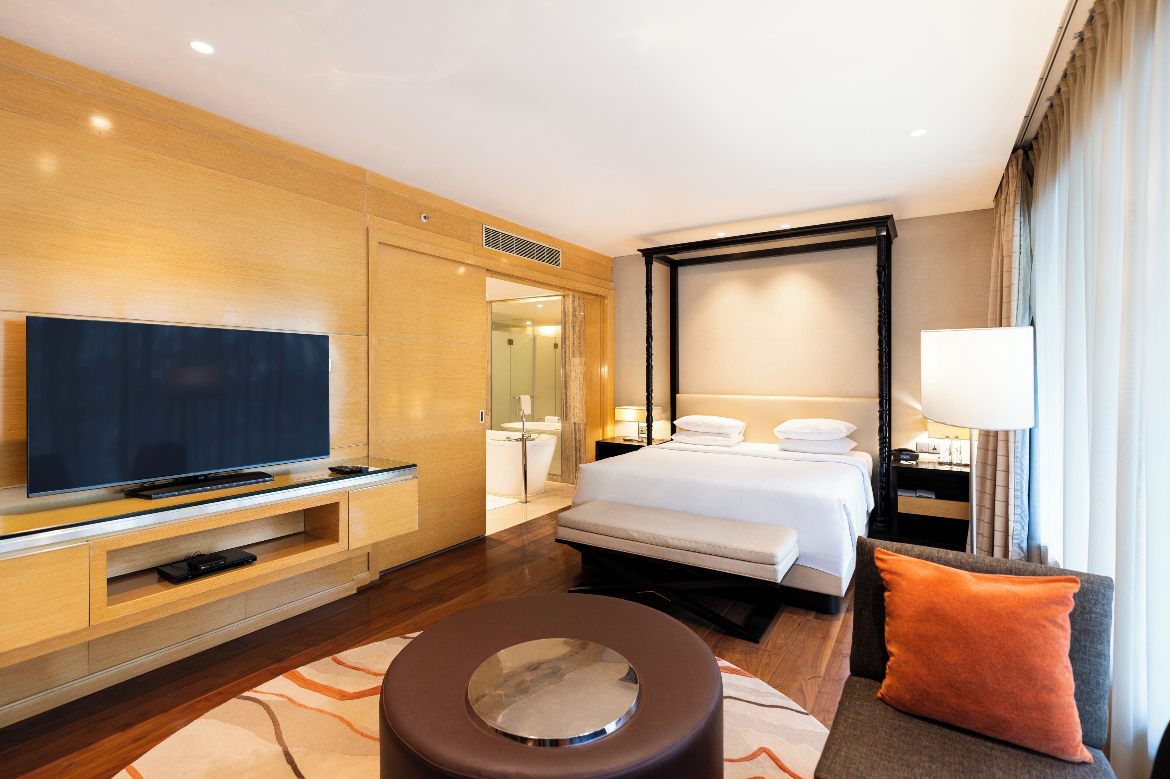 A hotel room with a TV, a bed, a bathroom, and a seating area.