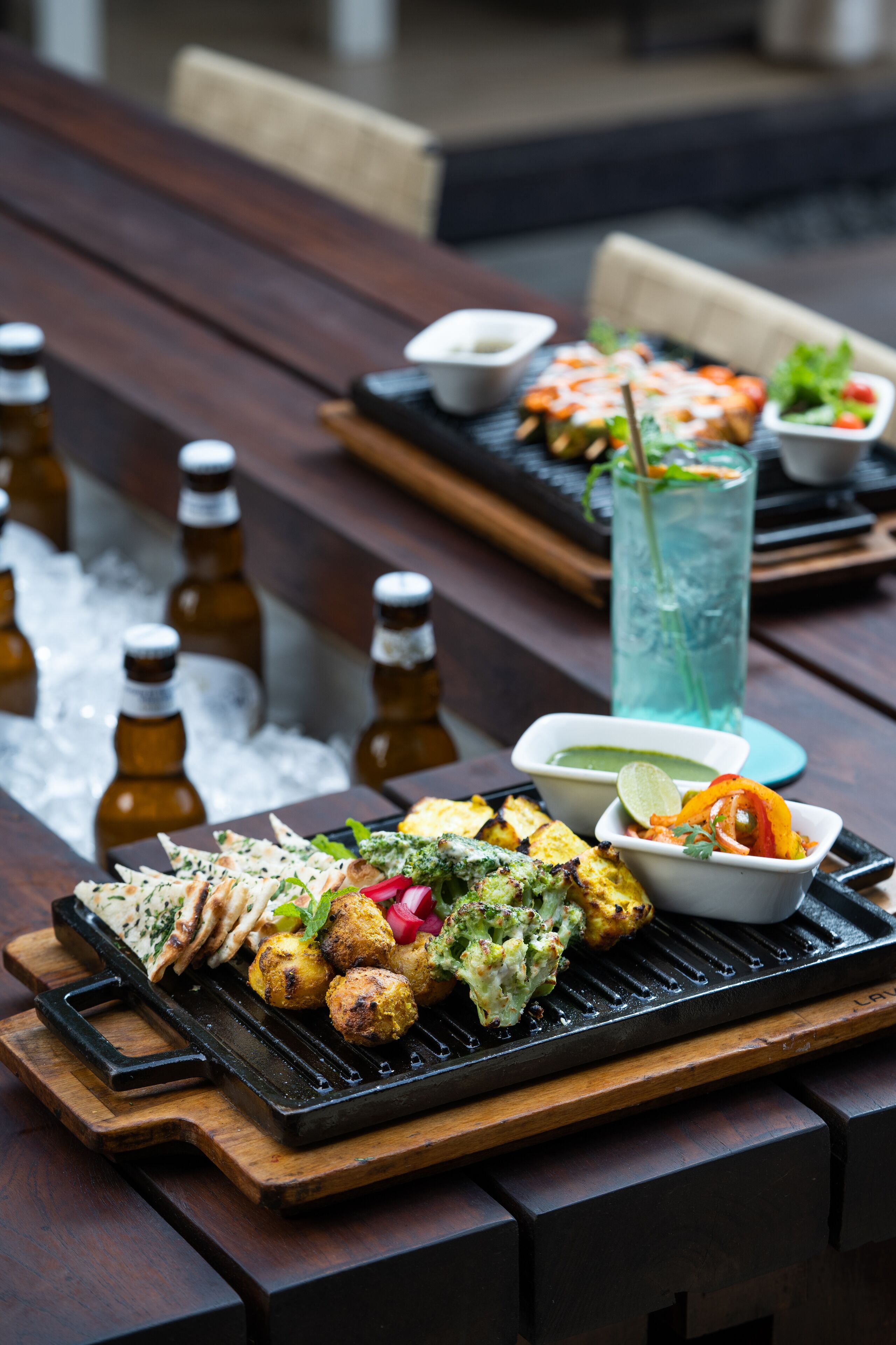 A dining table with various dishes, including grilled items and a drink.