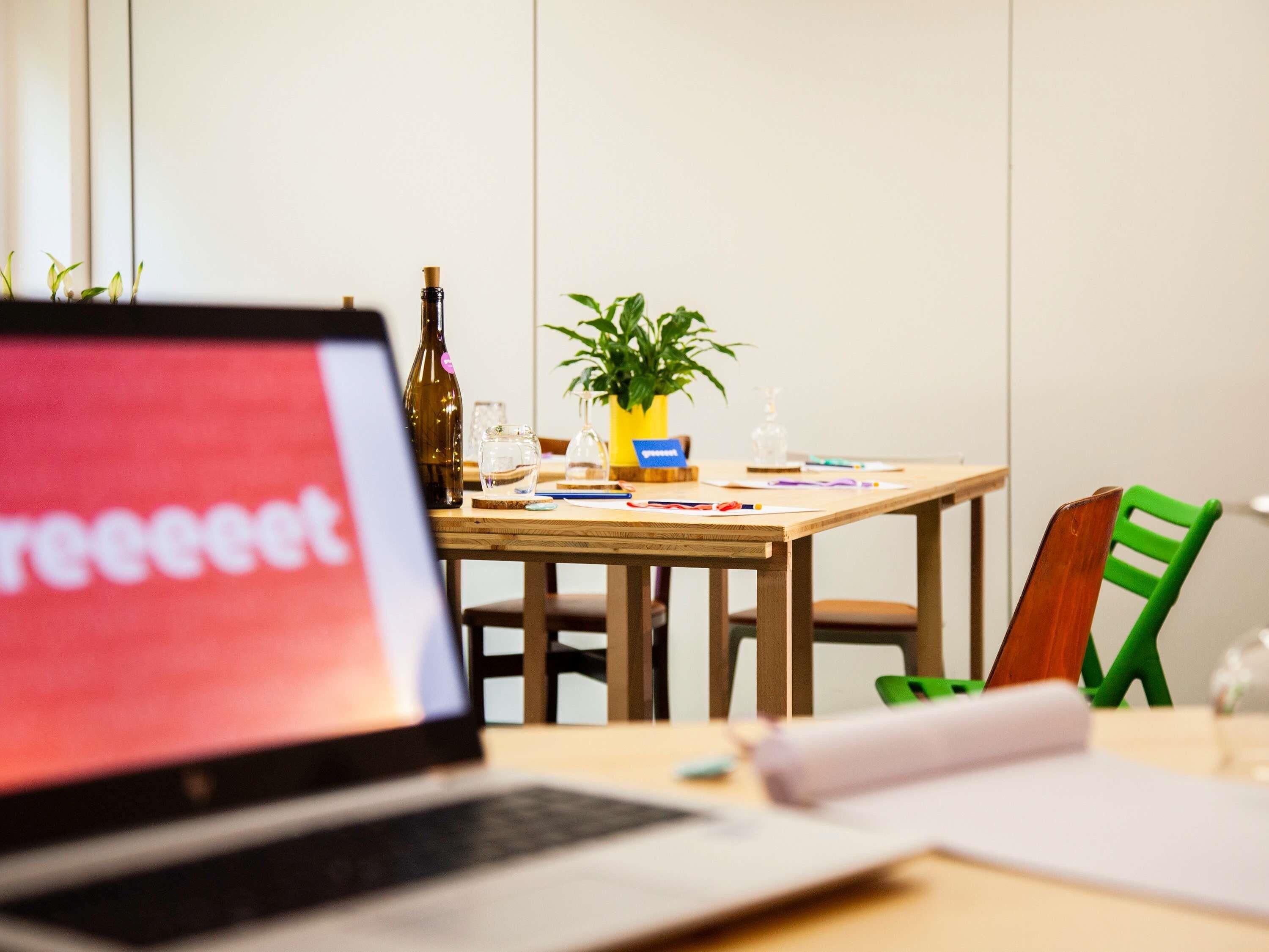 A laptop on a desk with a plant, a bottle, and some papers.