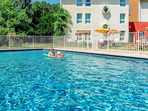 Una piscina al aire libre de temporada, sombrillas