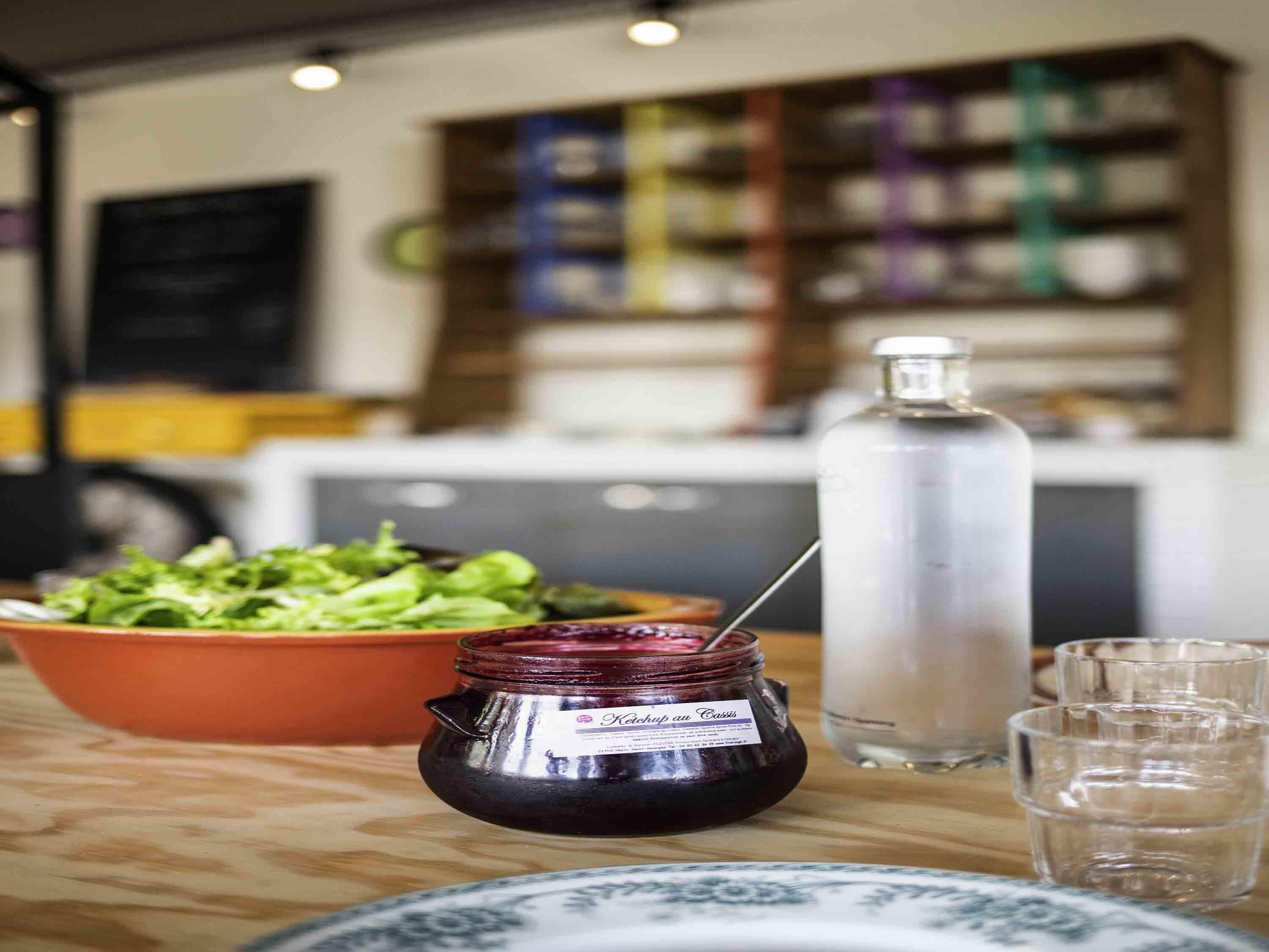 Una zona de cocina con un tazón de ensalada, un frasco de mermelada y una botella de agua sobre la encimera.