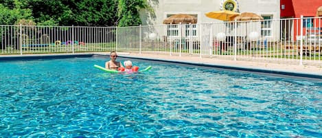Una piscina al aire libre de temporada, sombrillas