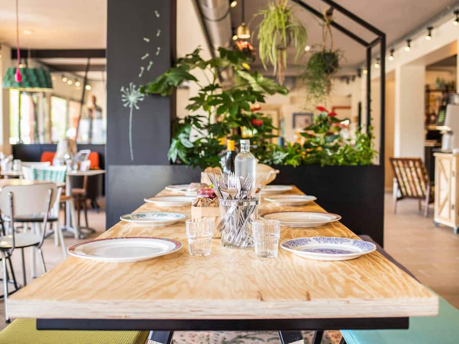 A restaurant with a long wooden table set for a meal, surrounded by chairs.