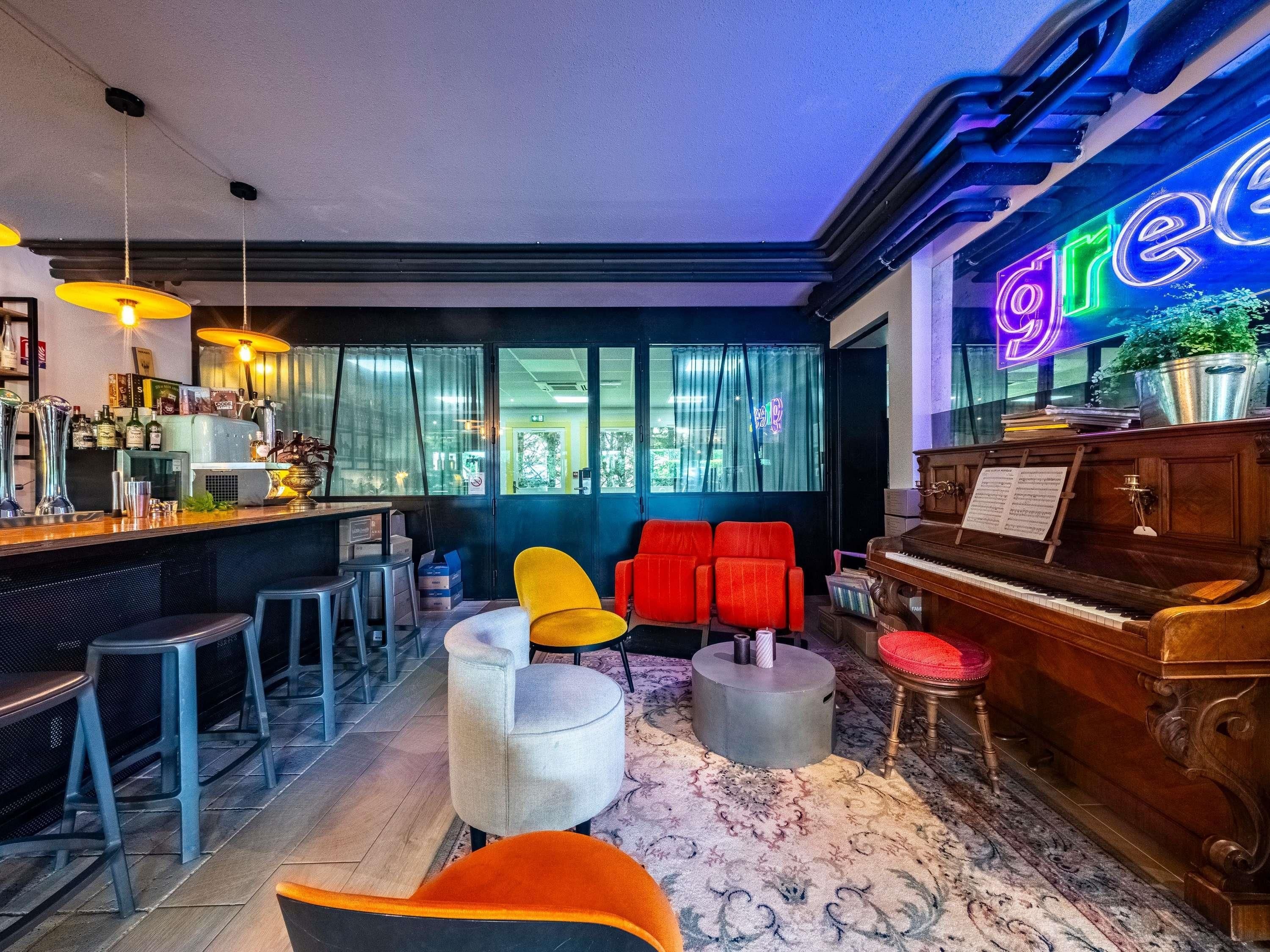 Een bar met krukken, een piano en een neonreclame.