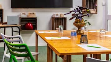 A conference room with a wooden table, chairs, a projector screen, and a plant.