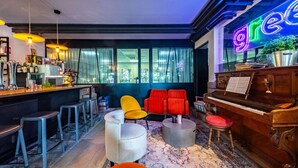 Een bar met krukken, een piano en een neonreclame.