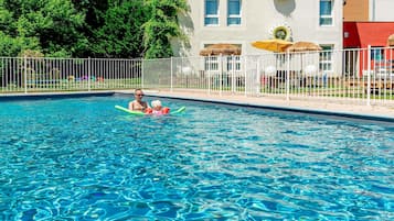 Una piscina al aire libre de temporada, sombrillas