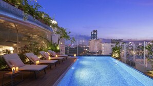 A rooftop pool with lounge chairs and a city view at dusk. - Silverland Ben Thanh (Ho Chi Minh City)