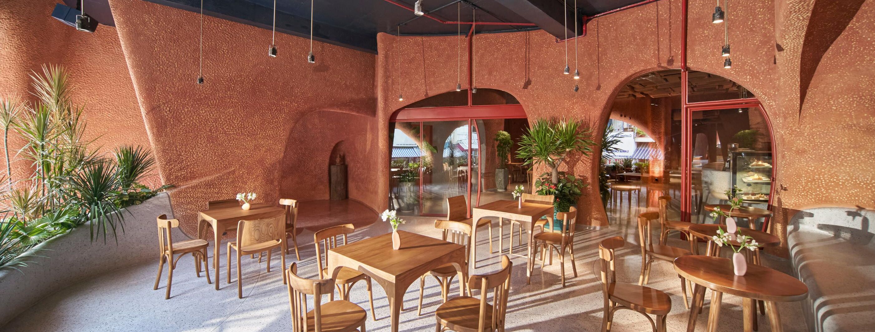 An indoor dining area with brick walls, wooden tables and chairs, and potted plants.