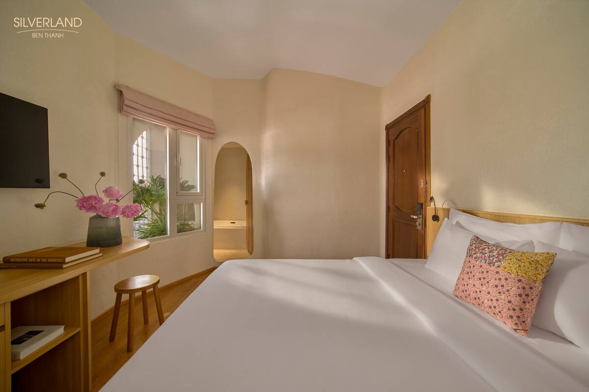 Una habitación de hotel con cama, escritorio, silla, ventana y puerta.