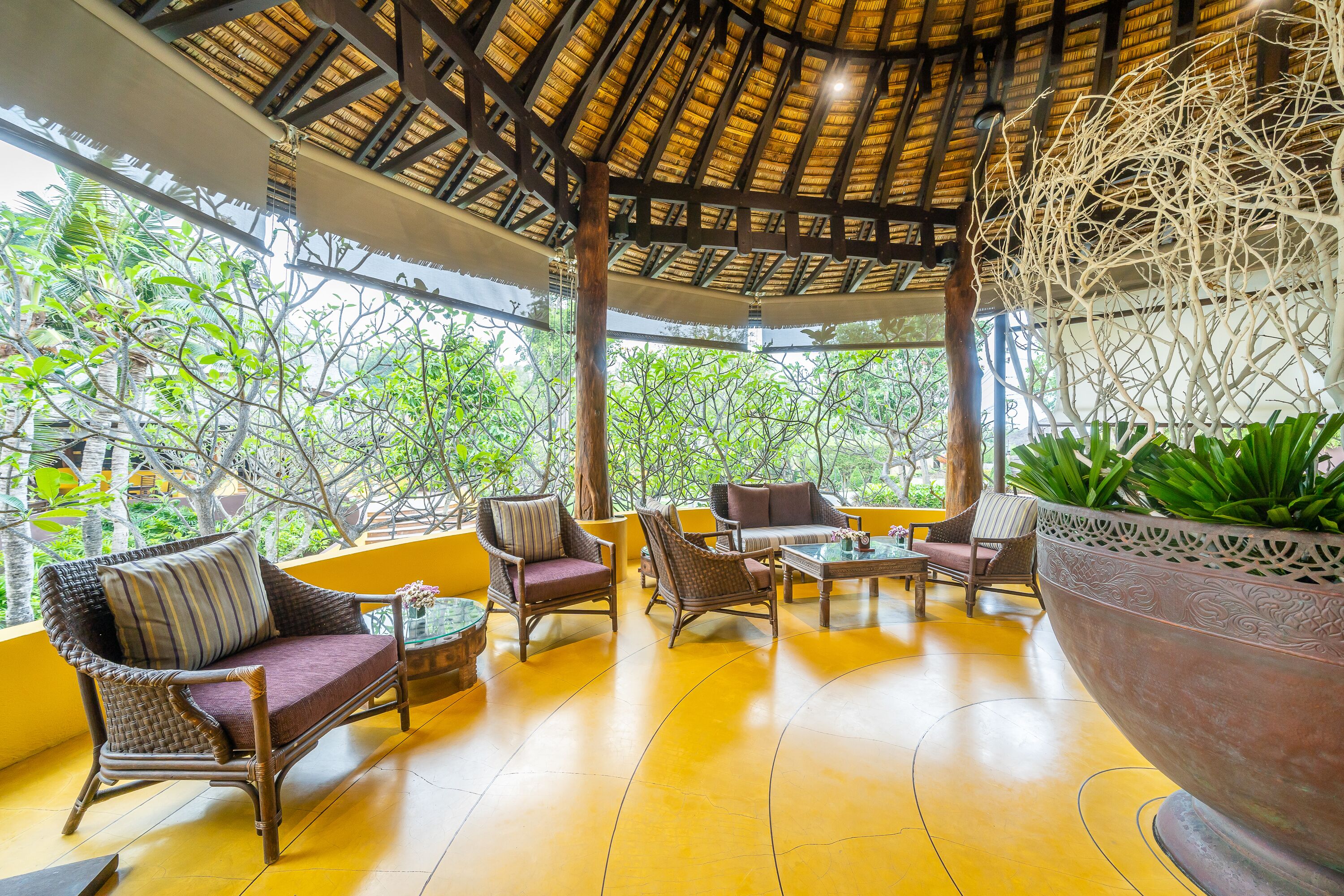 A covered outdoor seating area with wicker furniture and a large planter.