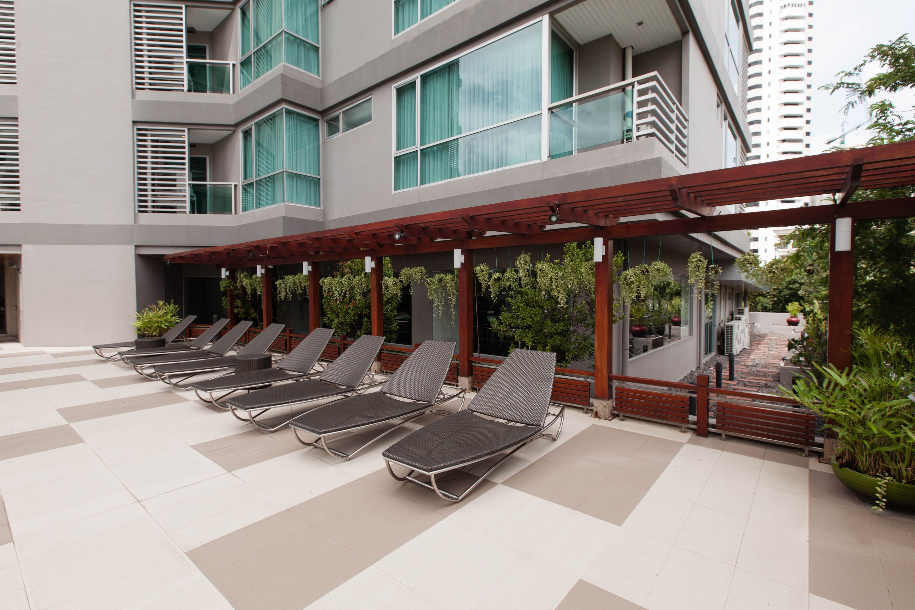 A modern outdoor lounge area with multiple sun loungers and potted plants.