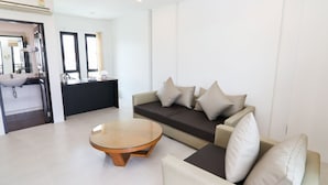 Una sala de estar moderna con un sofá, una mesa de centro y una zona de cocina al fondo.