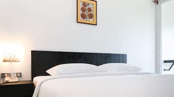 Una camera d'albergo con un letto, un comodino, un quadro appeso alla parete e una finestra.