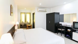 Habitación de hotel con una cama, un escritorio con computadora, televisión y armario.