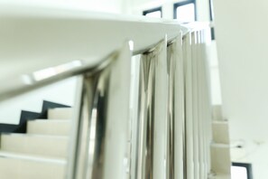 A staircase with a handrail and a view of a room with a window. - G House (Hua Hin)