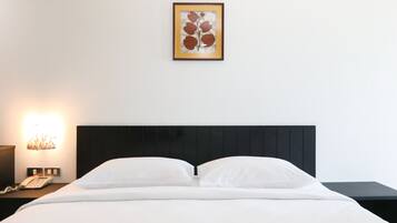 Une chambre d’hôtel avec un lit, une table de chevet avec une lampe et une œuvre d’art encadrée au mur.