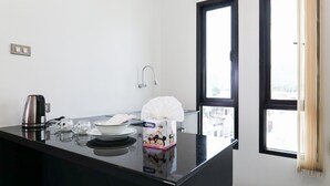 Una cocina pequeña con cafetera, caja de pañuelos y ventana con cortinas.