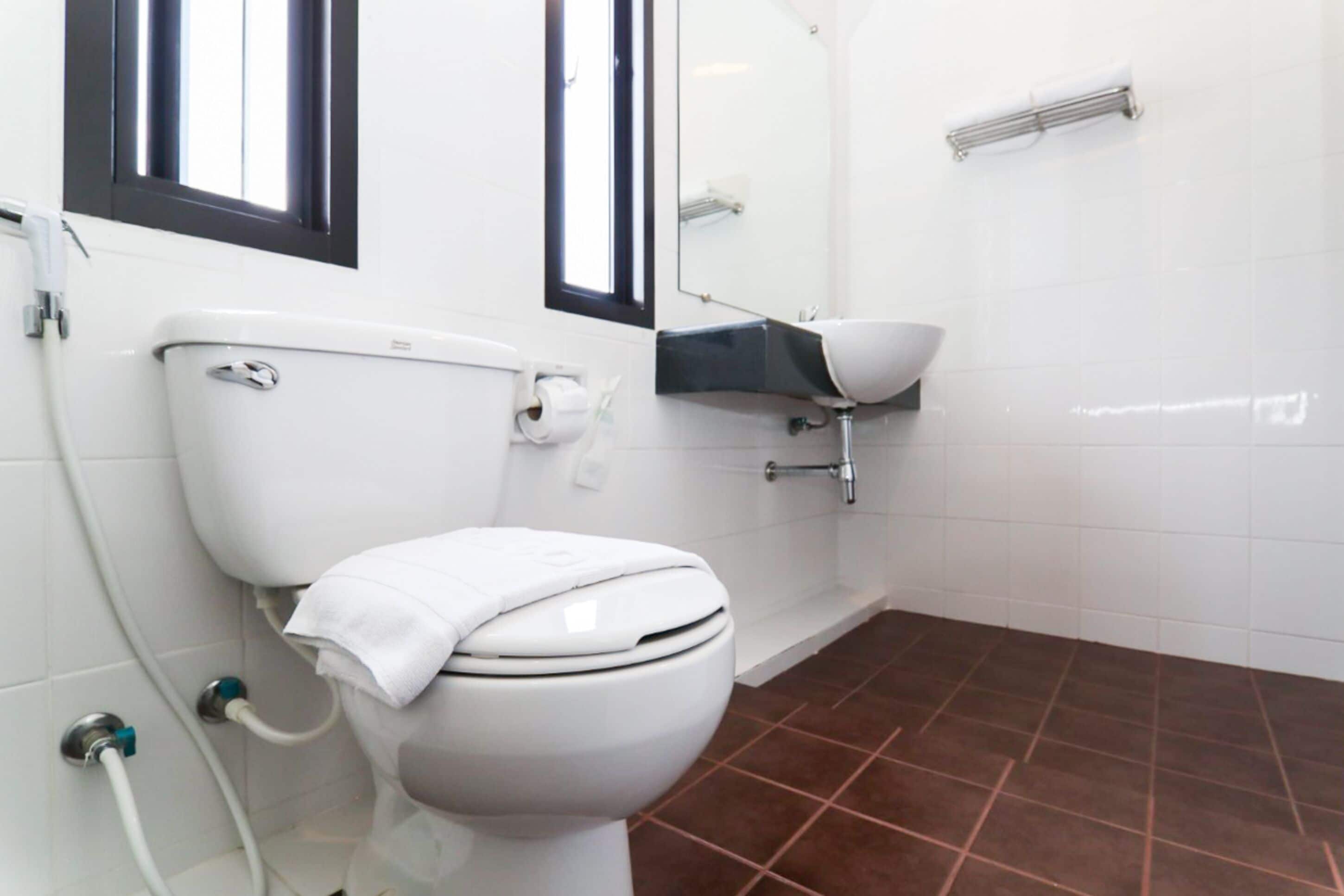 Een moderne badkamer met een wit toilet, een wastafel en een douche.