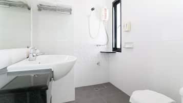 Un baño con lavamanos, espejo, ducha y toallero.