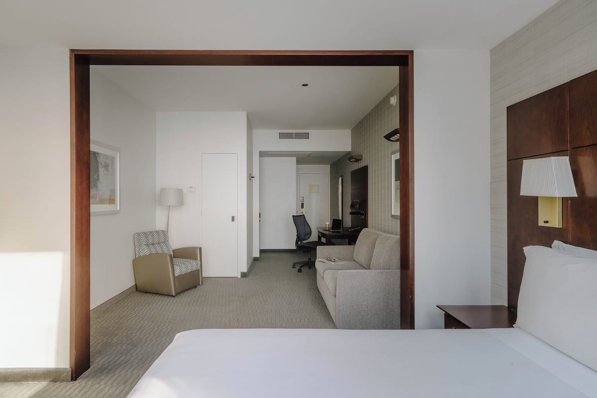 A hotel room with a bed, a desk, a chair, a sofa, and a small table.