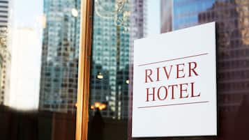 A sign for the River Hotel with a view of tall buildings in the background.