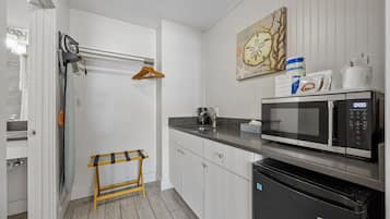 A modern kitchen with a microwave, a sink, and a wooden stool.