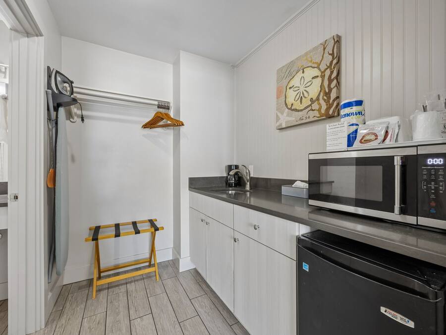A modern kitchen with a microwave, a sink, and a wooden stool.